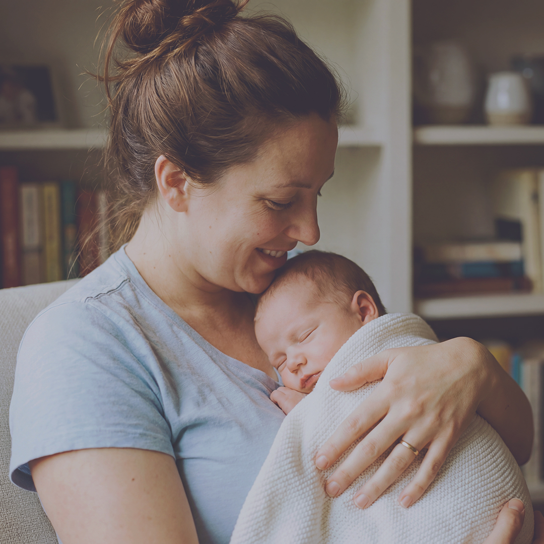 Mama mit schlafendem Baby im Wochenbett